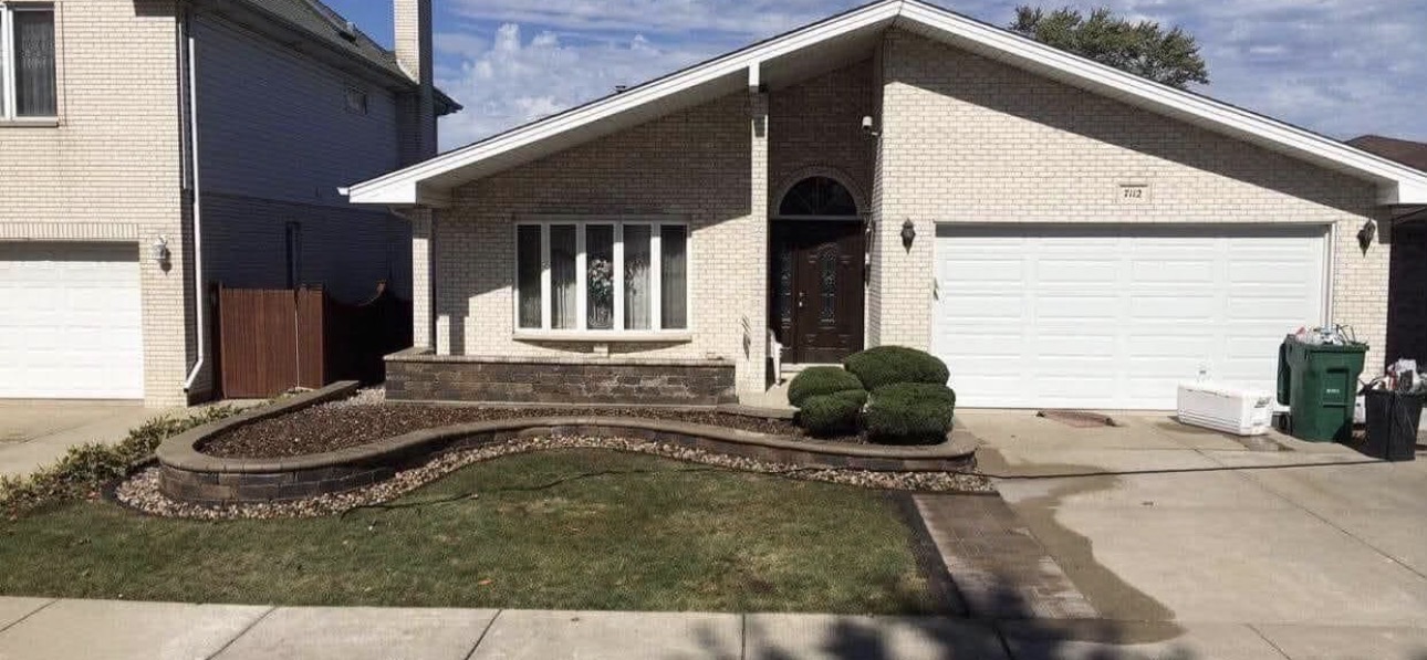 Residential property with curved brick border, trimmed shrubs and clean driveway
