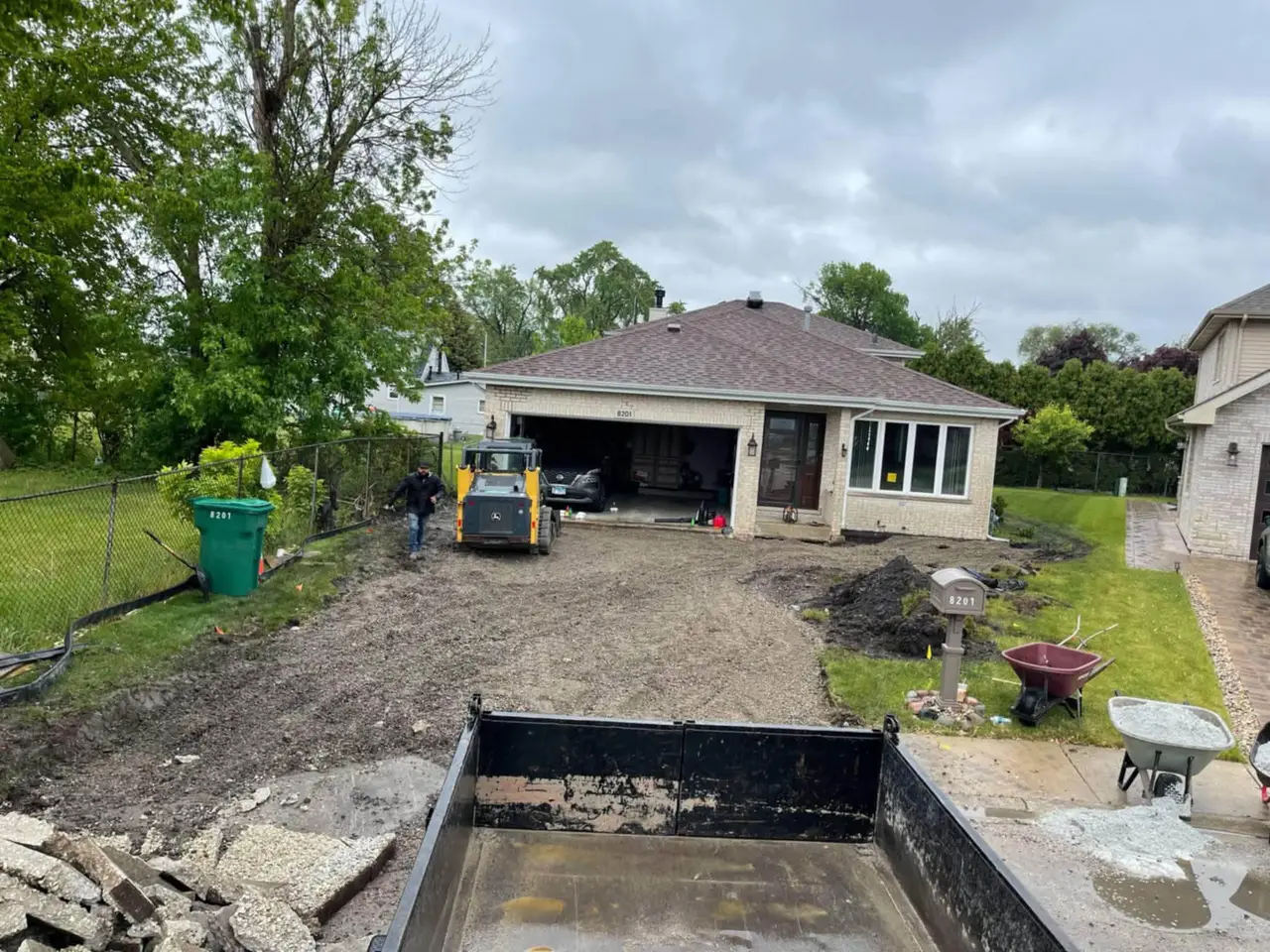 Driveway excavated down to gravel base with skid steer before paver installation