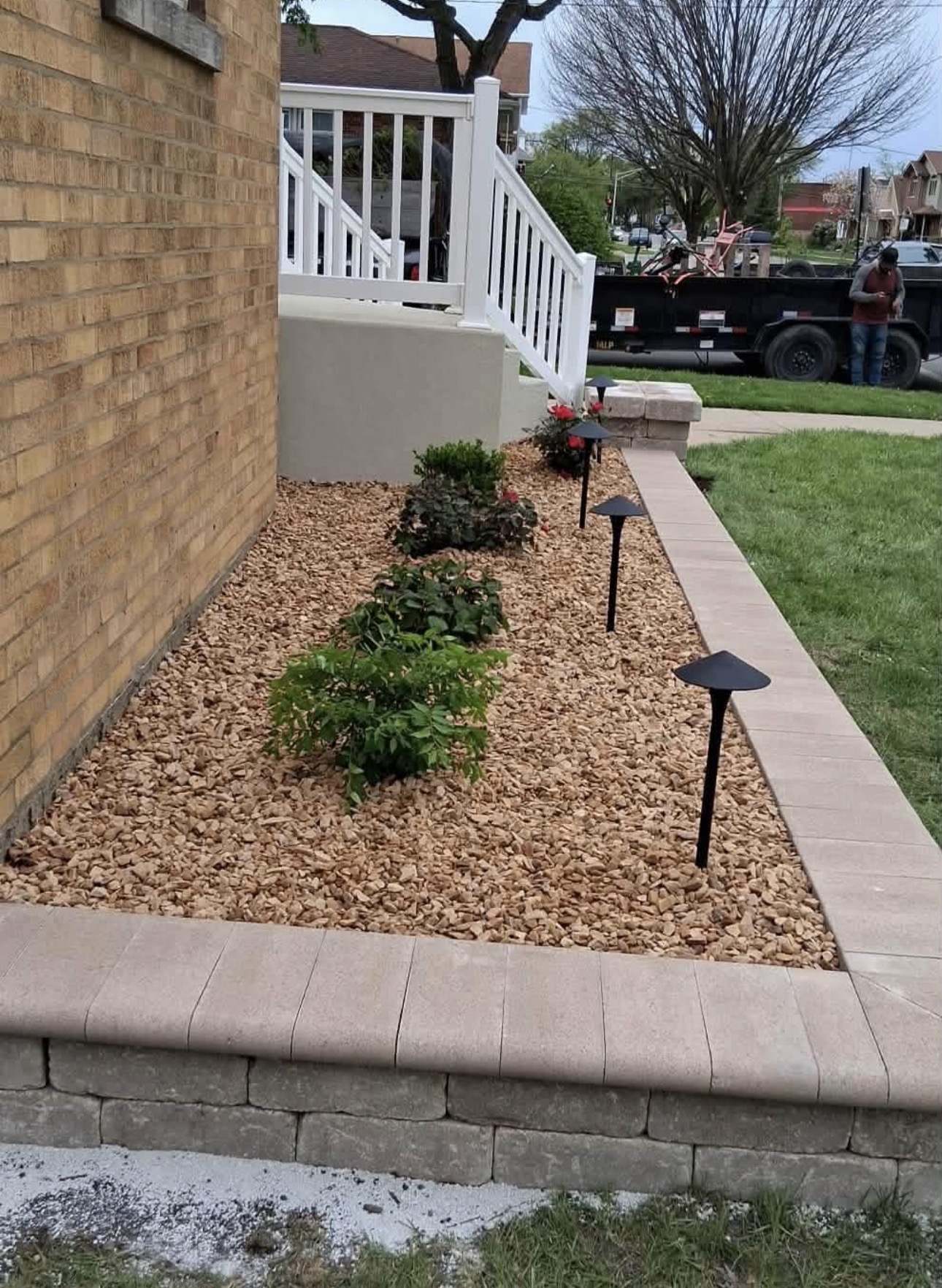 Capped stone border bed with decorative gravel, shrubs and path lighting